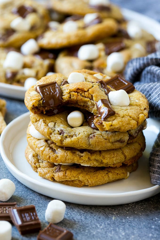 S'mores Cookies Recipe | Marshmallow Cookies #smores #marshmallow #chocolate #cookies #dessert #edsug A stack of S'mores cookies with a bite taken out of one.