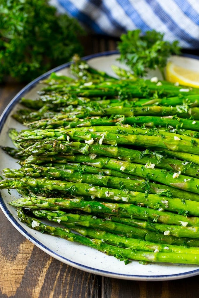 Roasted Asparagus Recipe | Baked Asparagus | Asparagus Side Dish #asparagus #garlic #sidedish #keto #lowcarb #dinner #edsug A serving plate of roasted asparagus topped with chopped parsley.
