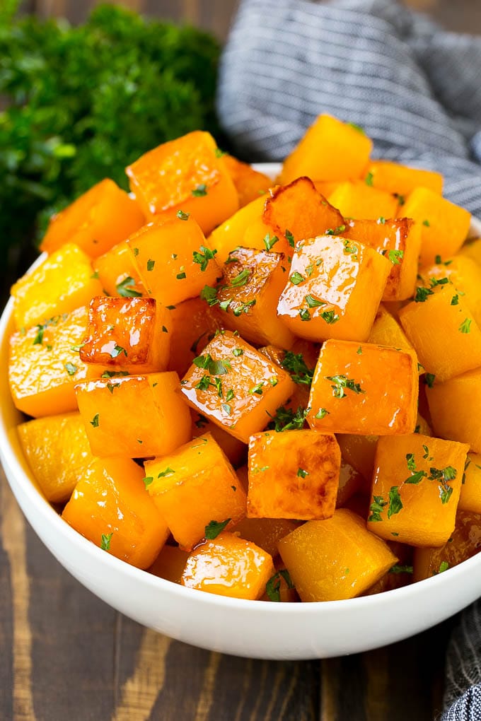 Roasted Butternut Squash Recipe | Baked Butternut Squash | Butternut Squash Side Dish #butternutsquash #squash #fall #vegetarian #dinner #edsug A bowl of roasted butternut squash made with brown sugar and maple syrup, then garnished with chopped parsley.