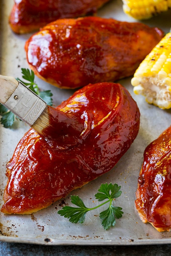 Smoked chicken breasts being brushed with BBQ sauce.