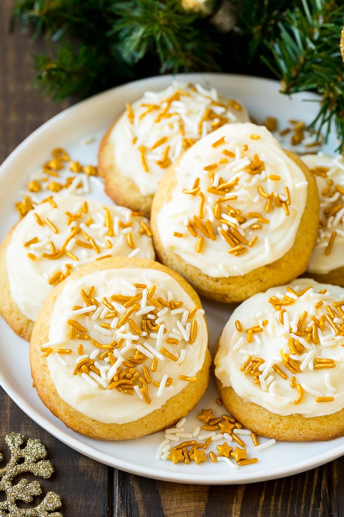 Eggnog Cookies Recipe | Holiday Cookies | Christmas Cookies #cookies #eggnog #baking #christmas #sprinkles #dessert #edsug Eggnog cookies topped with frosting and gold sprinkles on a serving plate.
