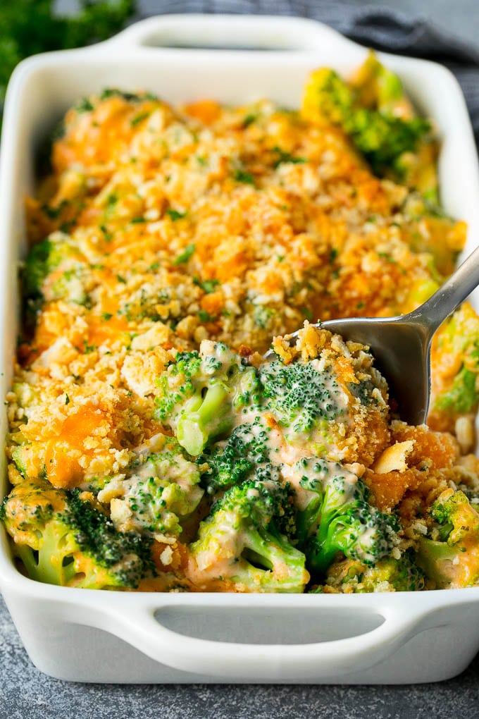 Broccoli Casserole Recipe | Broccoli and Cheese Casserole | Baked Broccoli #broccoli #cheese #casserole #sidedish #dinner #edsug A pan of broccoli casserole with a serving spoon in it.