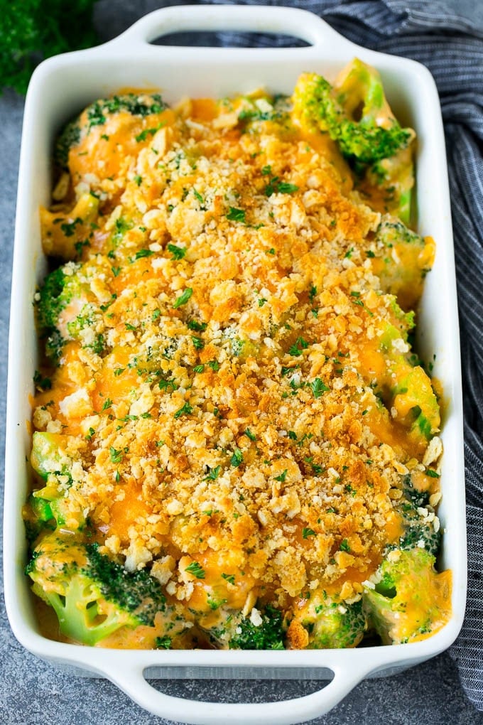 Broccoli Casserole Recipe | Broccoli and Cheese Casserole | Baked Broccoli #broccoli #cheese #casserole #sidedish #dinner #edsug A pan of broccoli casserole topped with crackers, melted cheese and parsley.
