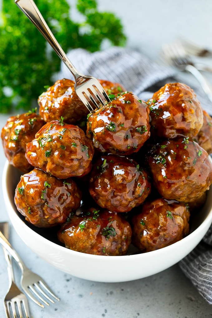Sweet and Sour Meatballs Recipe | Slow Cooker Meatballs | Crockpot Meatballs | Cocktail Meatballs #meatballs #beef #slowcooker #crockpot #dinner #appetizer #edsug A bowl of sweet and sour meatballs with a cocktail fork in it.