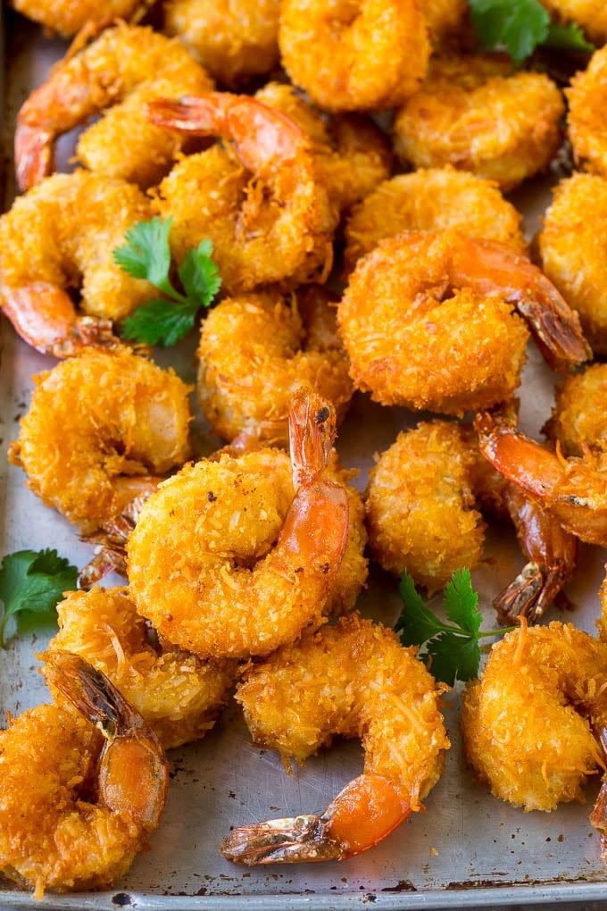 Coconut Shrimp Recipe | Fried Shrimp | Shrimp Appetizer #shrimp #coconut #appetizer #seafood #dinner #edsug A pile of crispy coconut shrimp on a sheet pan with cilantro leaves for garnish.