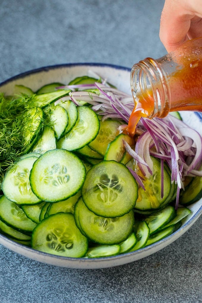 Cucumber Salad Recipe | Cucumber Dill Salad | Cucumber Recipe #cucumbers #salad #glutenfree #sidedish #edsug Dressing being poured over sliced vegetables and fresh dill.