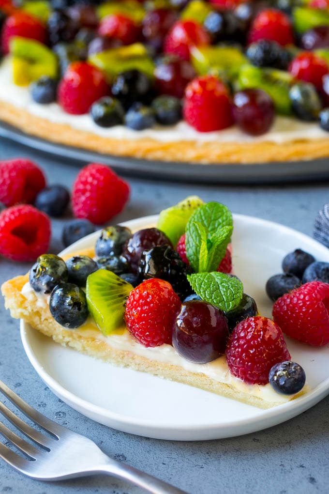 Fruit Pizza Recipe | Dessert Pizza | Fruit Dessert #cookie #fruit #pizza #dessert #sweets #edsug A slice of fruit pizza topped with cream cheese frosting and berries.