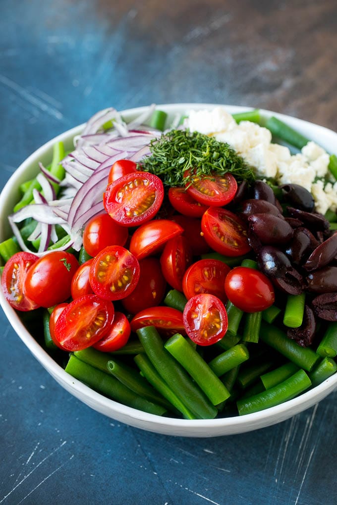 Green Bean Salad Recipe | String Bean Salad | Chopped Salad #greenbeans #tomatoes #olives #salad #cleaneating #lowcarb #glutenfree #edsug Vegetables like cherry tomatoes, red onion and olives in a bowl with feta cheese.