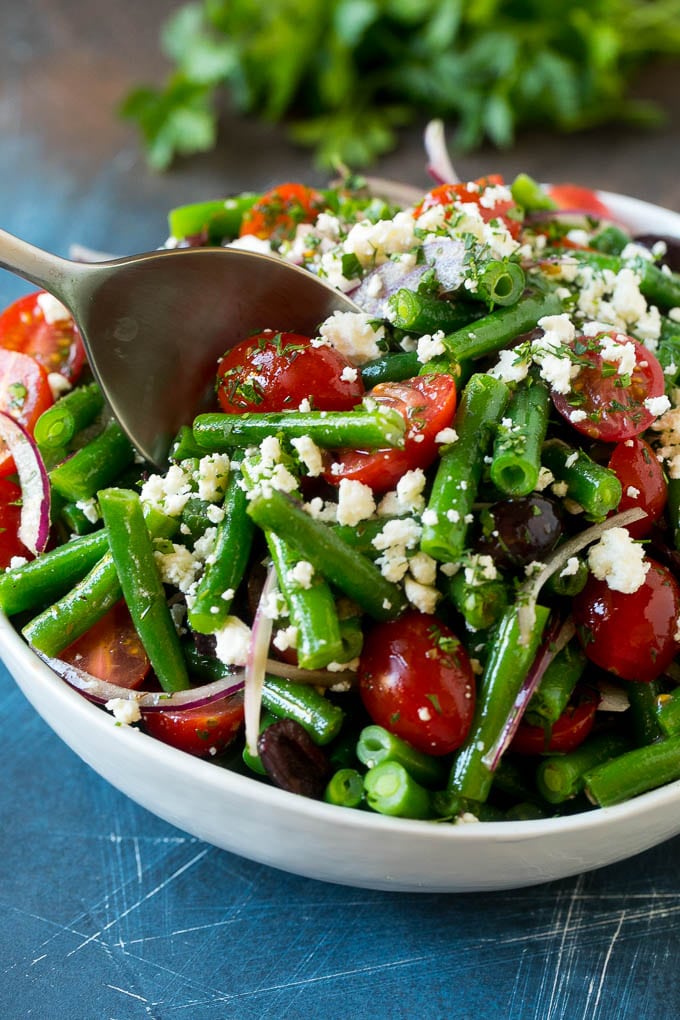 Green Bean Salad Recipe | String Bean Salad | Chopped Salad #greenbeans #tomatoes #olives #salad #cleaneating #lowcarb #glutenfree #edsug A serving spoon in a bowl of green bean salad.