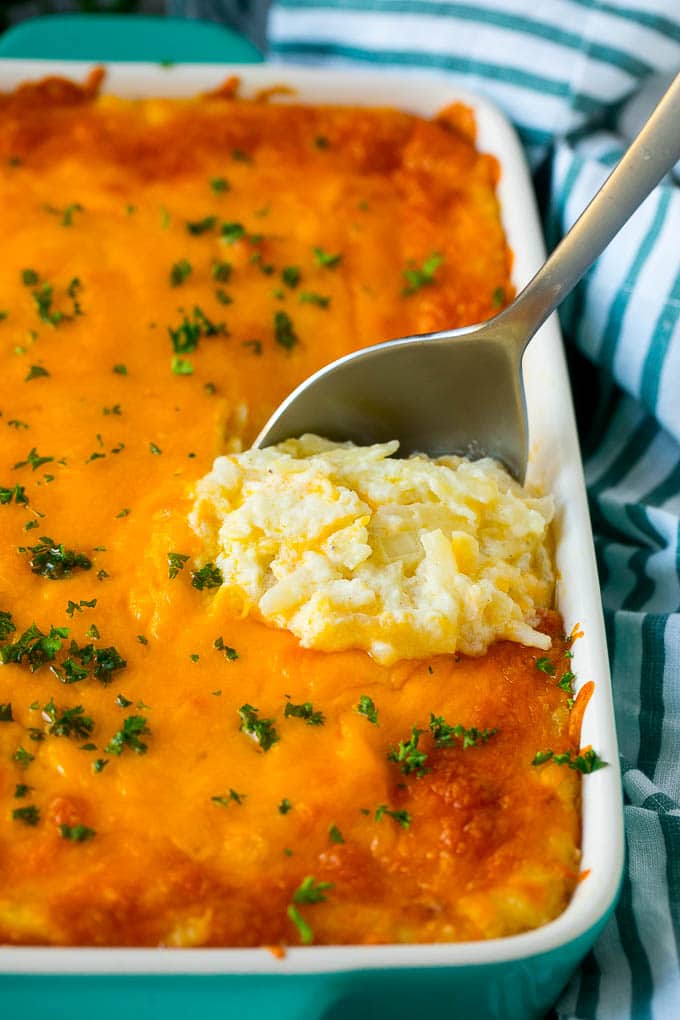 Hash Brown Casserole | Potato Casserole | Hash Brown Side Dish #potatoes #cheese #casserole #sidedish #edsug Hash brown casserole with potatoes, cheddar cheese, onions and sour cream, with a serving spoon in the dish.
