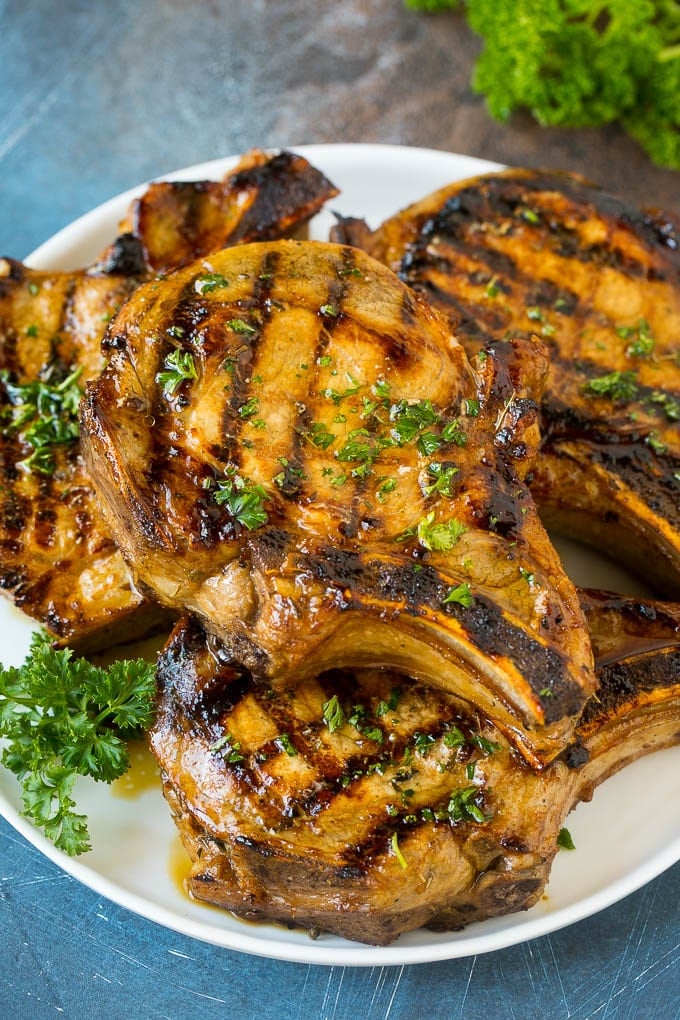 Pork Chop Marinade Recipe | Marinated Pork Chops | Grilled Pork Chops #pork #porkchops #grilling #dinner #edsug Pork chop marinade on grilled pork chops. The pork chops are on a serving plate garnished with parsley.