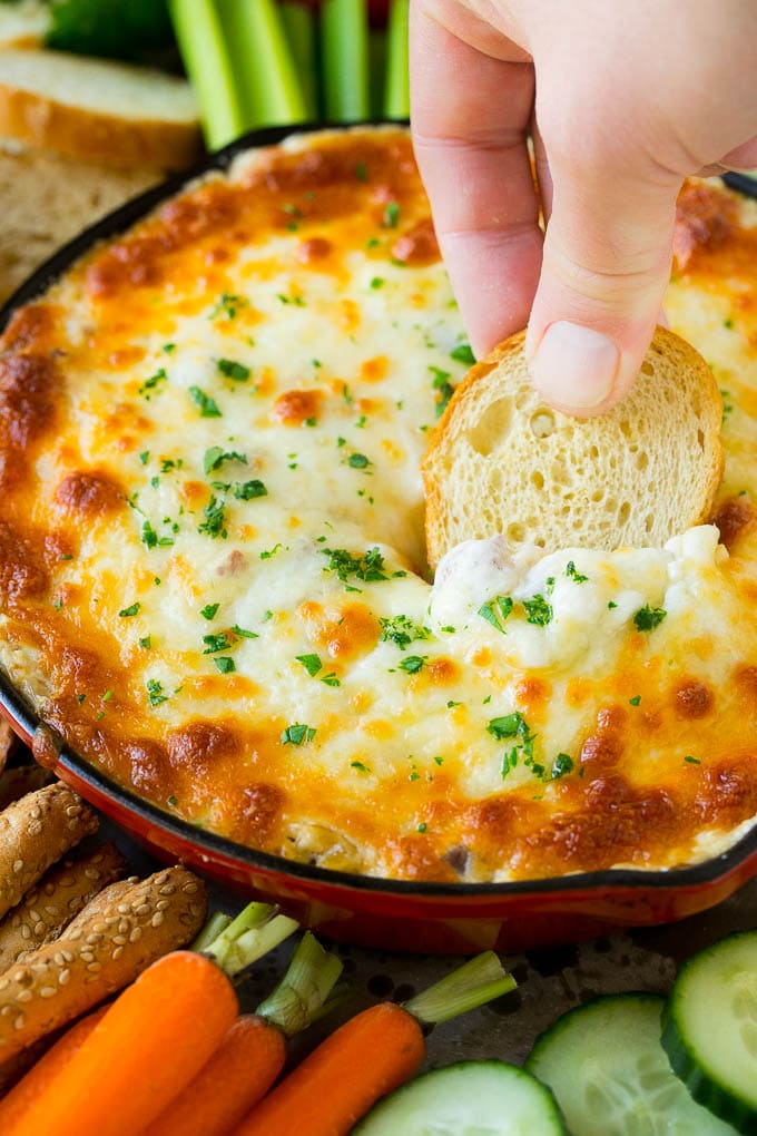 Reuben Dip Recipe | Corned Beef Dip | Cheese Dip #dip #cheese #cornedbeef #appetizer #lowcarb #keto #edsug A hand scooping out a serving of Reuben dip with baguette.