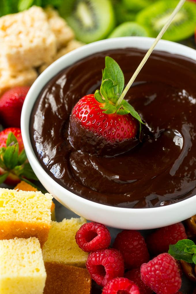 Chocolate Fondue Recipe | Chocolate Sauce | Chocolate Dip #chocolate #dessert #glutenfree #fondue #edsug A strawberry on a skewer dipped into a bowl of chocolate fondue.