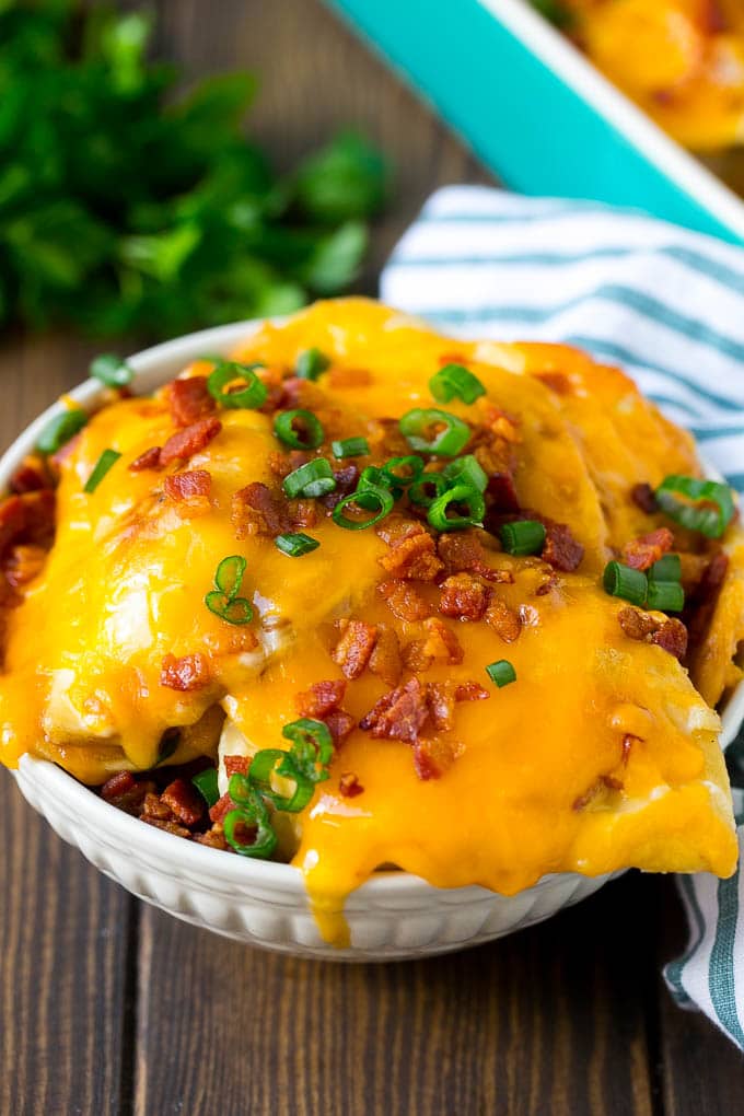 Pierogi Casserole Recipe | Potato Casserole #pierogis #casserole #bacon #cheddar #dinner #edsug A bowl of pierogi casserole topped with cheddar cheese and bacon.