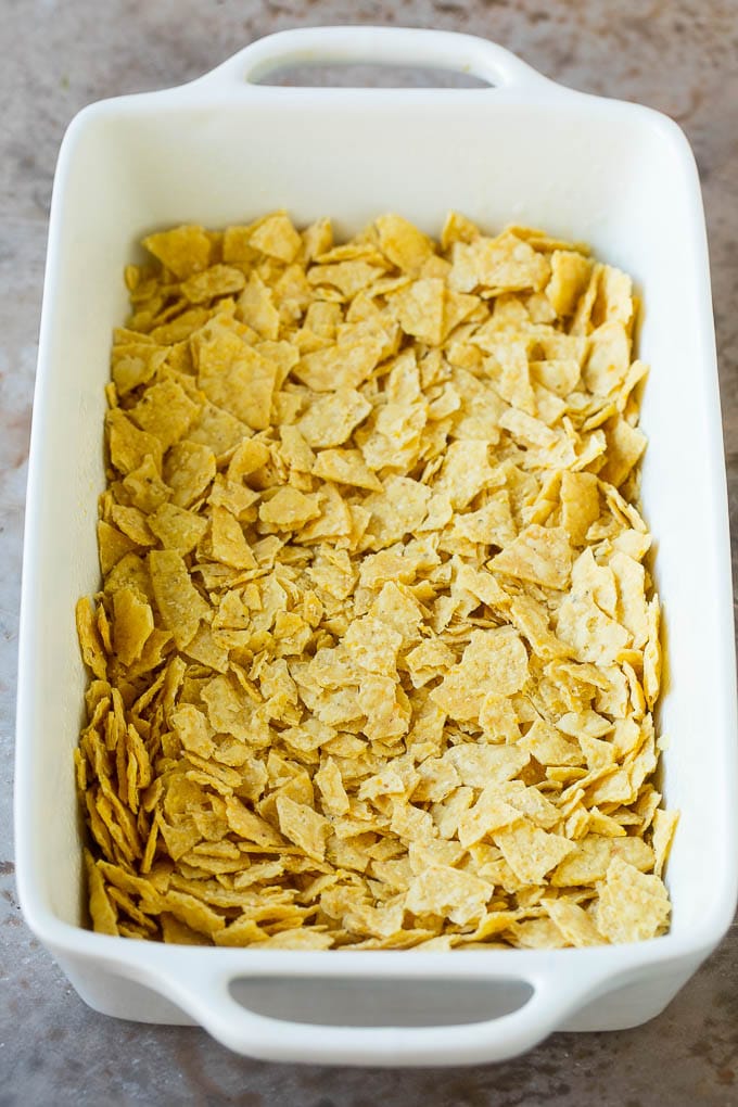 Taco Casserole Recipe | Mexican Casserole | Beef Casserole #casserole #tacos #beef #dinner #cheese #edsug Crushed tortilla chips in a casserole dish.