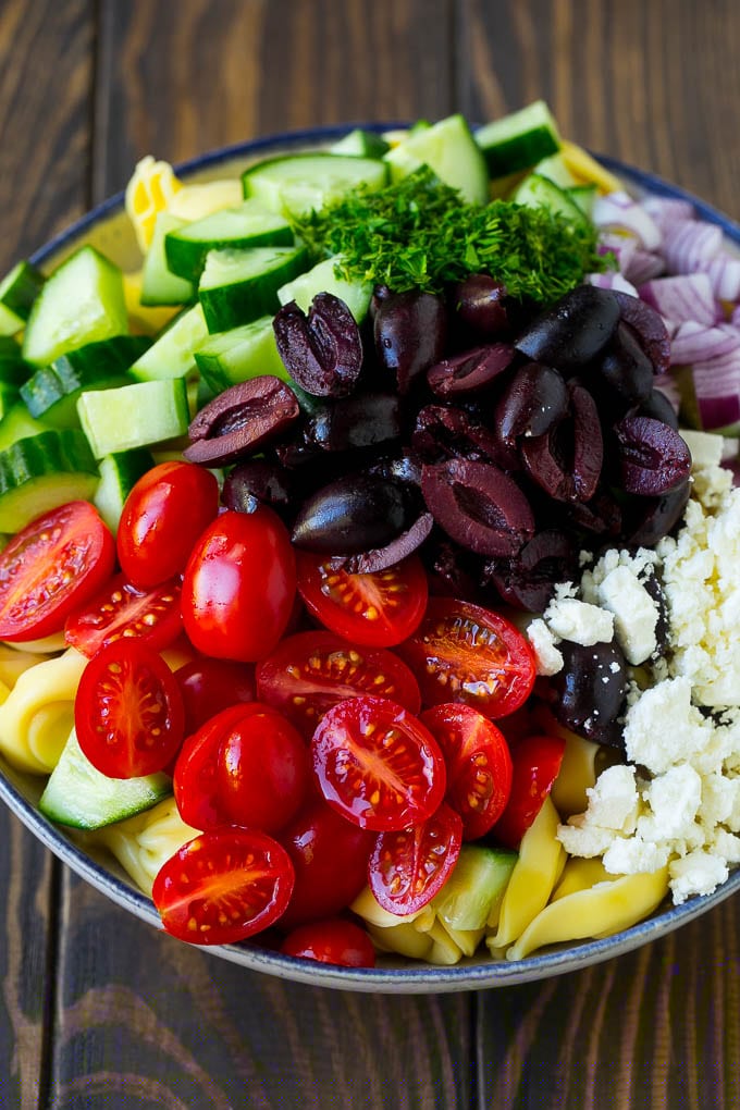 Greek Tortellini Salad Recipe | Pasta Salad | Tortellini Salad | Greek Salad #greek #tortellini #pasta #salad #cucumbers #olives #dinner #edsug Tortellini in a bowl topped with olives, tomatoes, cucumber and feta cheese.