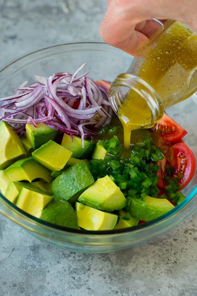 Tomato Avocado Salad Recipe | Avocado Salad | Tomato Salad #salad #tomato #avocado #glutenfree #cleaneating #dinner #edsug #healthy Dressing being poured over chopped veggies.