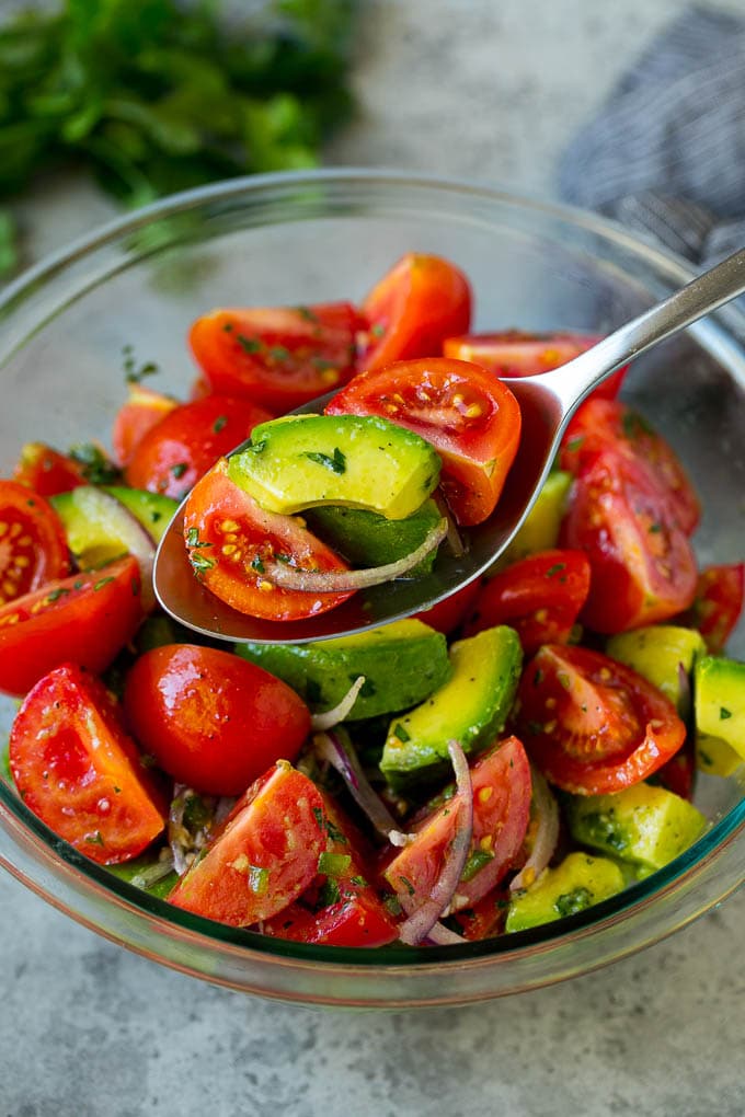 Tomato Avocado Salad Recipe | Avocado Salad | Tomato Salad #salad #tomato #avocado #glutenfree #cleaneating #dinner #edsug #healthy A serving spoon of veggies in a lime dressing.