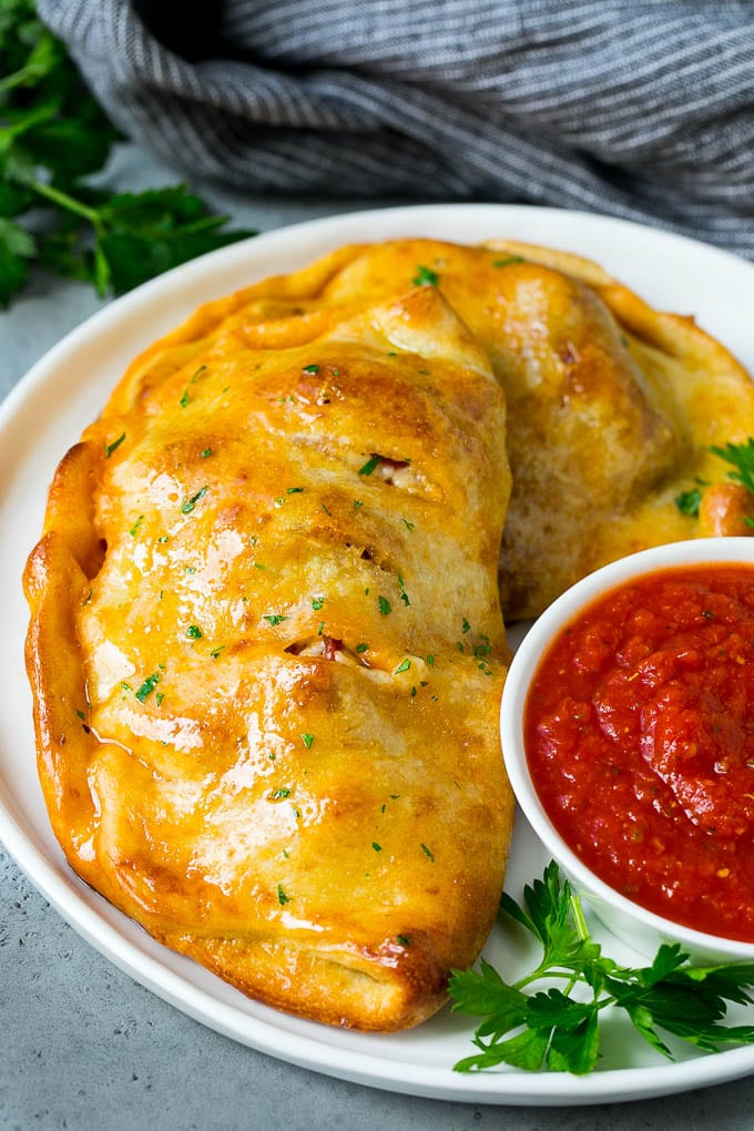 Calzone Recipe | Pizza Pockets #pizza #calzone #pepperoni #sausage #peppers #dinner #edsug #cheese A homemade calzone served with pizza sauce.