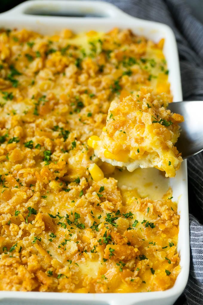 Scalloped Corn | Corn Casserole #corn #casserole #cheese #sidedish #dinner #edsug A serving spoon lifting out a portion of scalloped corn.