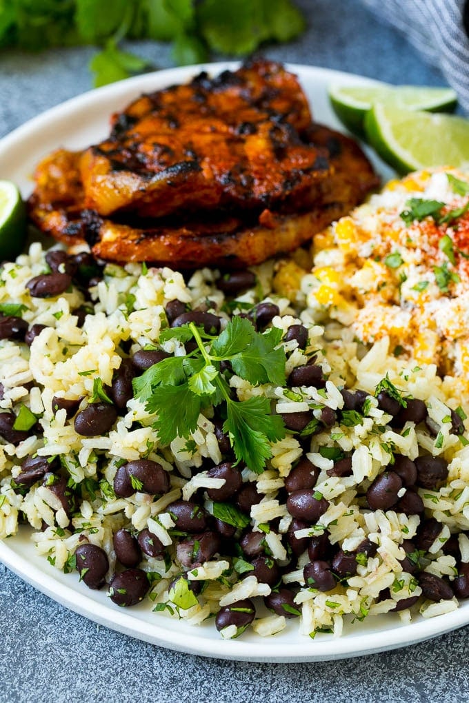 Black Beans and Rice Recipe | Cuban Black Beans | Beans and Rice #beans #rice #blackbeans #sidedish #glutenfree #dinner #edsug A plate of black beans and rice with grilled pork and Mexican corn.