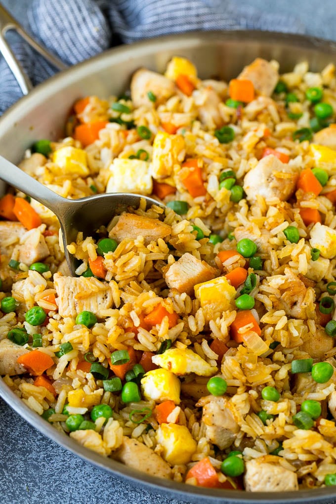 Chicken Fried Rice Recipe | Chinese Fried Rice #rice #chicken #peas #carrots #sidedish #dinner #edsug A serving spoon in a pan of chicken fried rice.