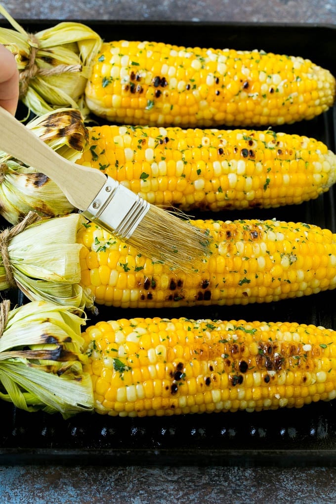 Grilled Corn on the Cob Recipe | Corn Recipe #corn #grilling #summer #sidedish #dinner #edsug Cobs being brushed with herb butter.