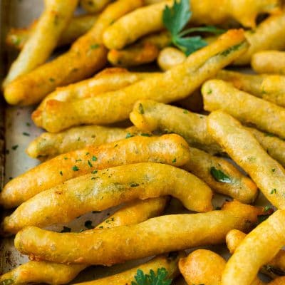 A sheet pan of fried green beans garnished with chopped parsley.