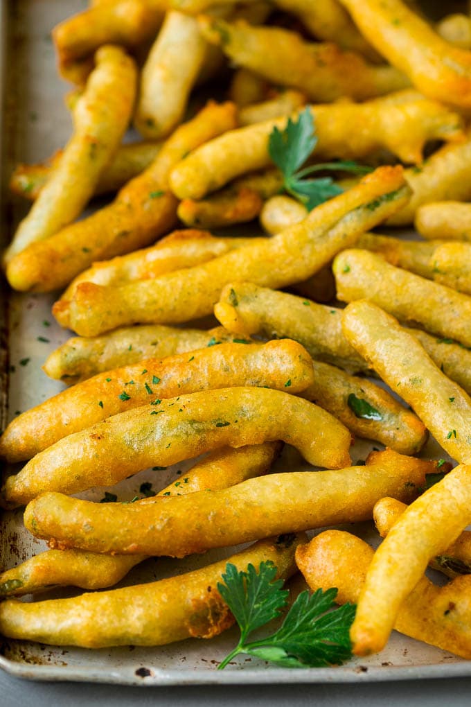 Fried Green Beans Recipe | Green Beans #greenbeans #appetizer #snack #edsug A sheet pan of fried green beans garnished with chopped parsley.