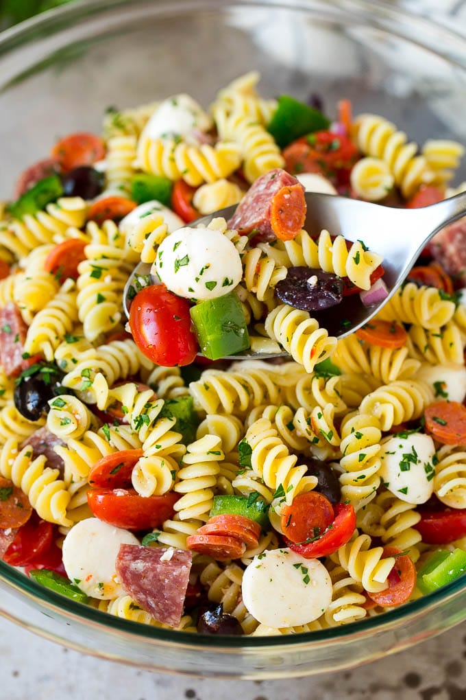 Italian Pasta Salad | Pasta Salad Recipe #pasta #salad #pastasalad #pepperoni #salami #olives #cheese #sidedish #edsug A serving spoon in a bowl of Italian style pasta salad.