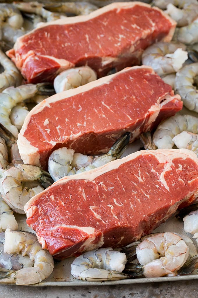 Surf and Turf Recipe | Seared Steak #steak #shrimp #keto #lowcarb #dinner #edsug Raw steaks and shrimp on a sheet pan.