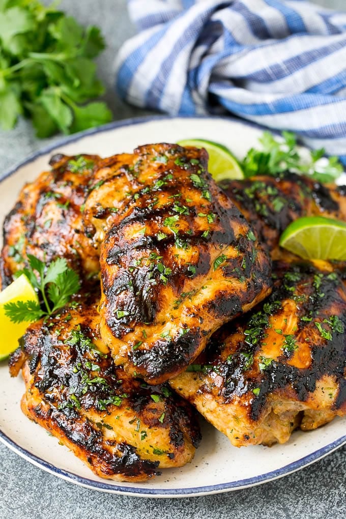 Grilled Chicken Thighs Recipe | Marinated Chicken Thighs #chicken #grilling #marinade #dinner #cilantro #lime #edsug Grilled chicken thighs with a garnish of cilantro and lime wedges.