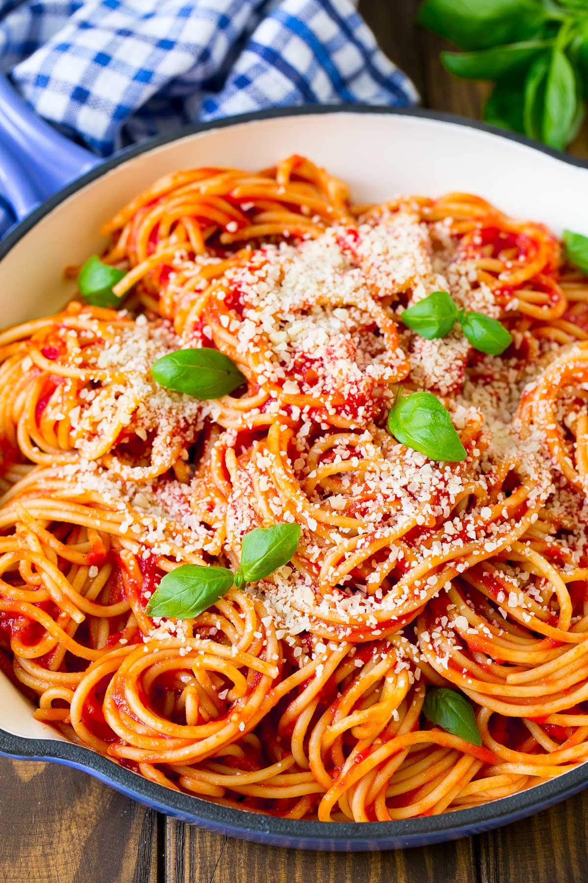 A pan of pasta pomodoro topped with cheese and basil.