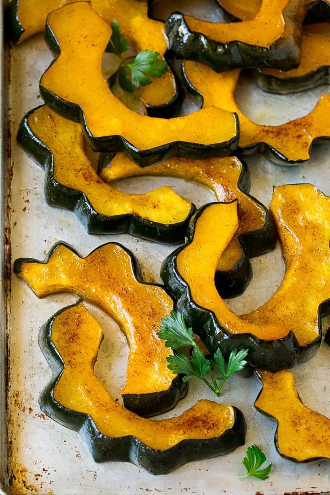 Roasted Acorn Squash | Acorn Squash Recipe #squash #winter #sidedish #dinner #edsug Sliced of cinnamon roasted acorn squash on a sheet pan.