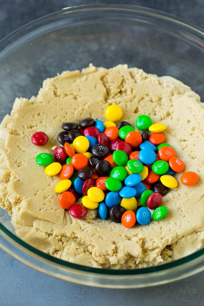 M&M Cookies Recipe #cookies #chocolate #baking #dessert #sweets #edsug A bowl of cookie dough with chocolate candies in it.