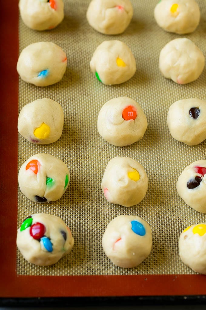 M&M Cookies Recipe #cookies #chocolate #baking #dessert #sweets #edsug Balls of cookie dough on a baking sheet.