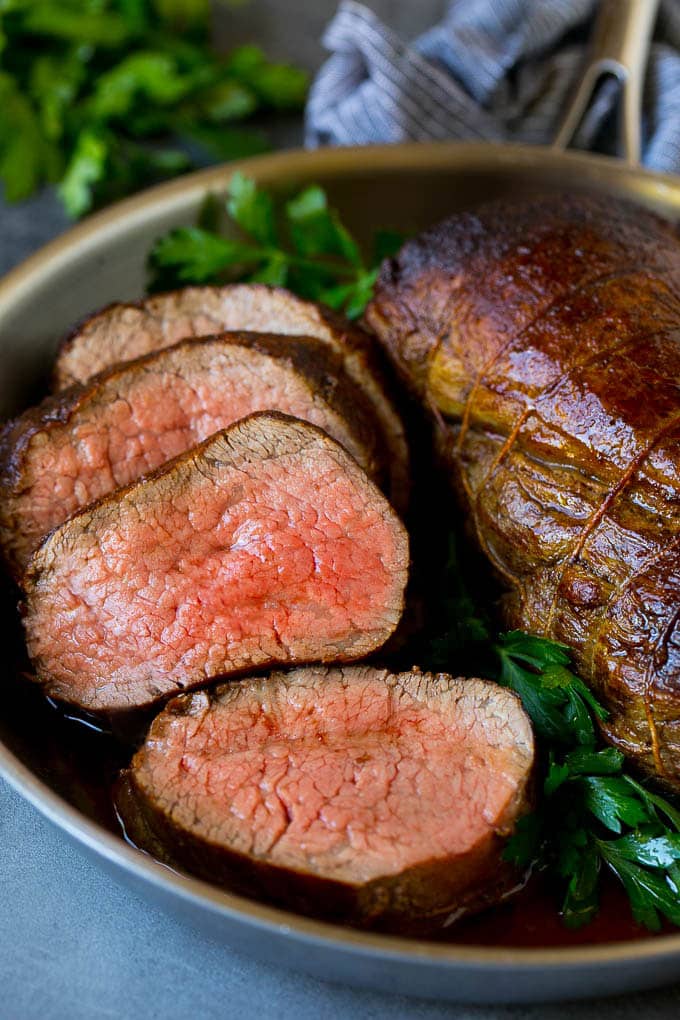 Beef Tenderloin with Garlic Butter #beef #steak #dinner #edsug A sliced beef tenderloin recipe in a pan, garnished with fresh parsley.