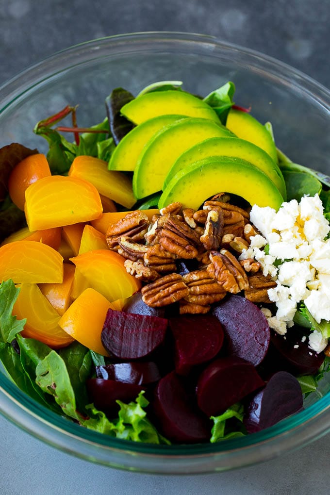 Beet Salad Recipe #beets #avocado #feta #salad #dinner #edsug Red and yellow beets, salad greens, feta cheese, avocado and pecans in a bowl.