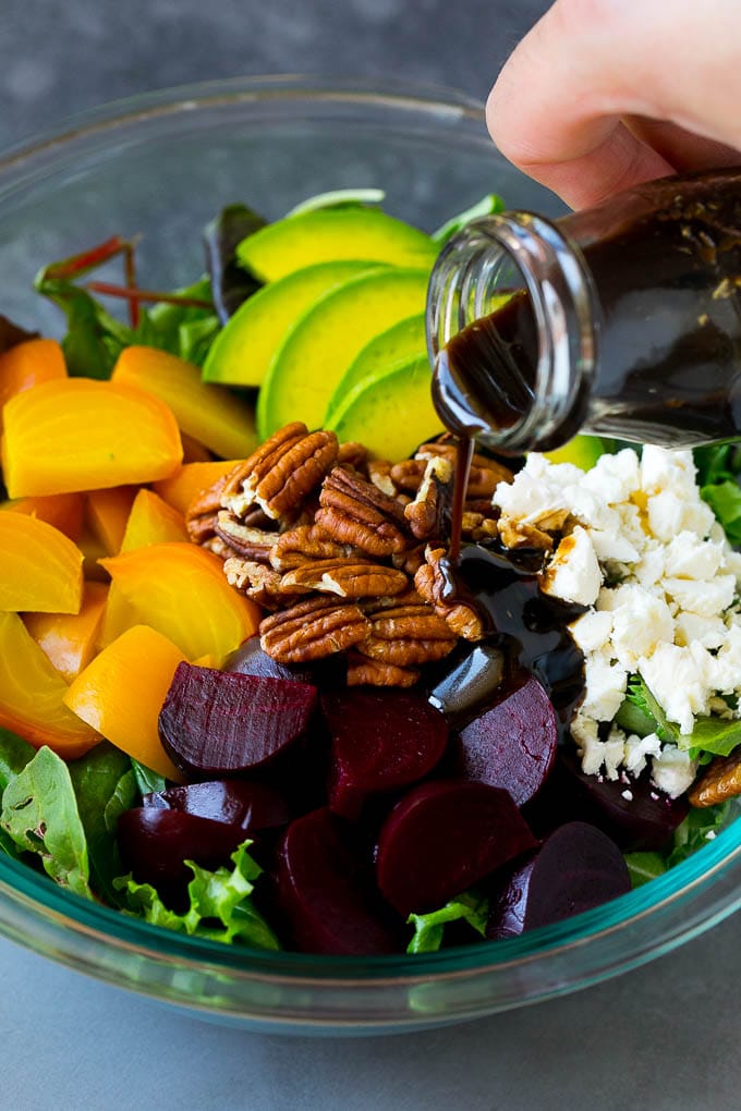 Beet Salad Recipe #beets #avocado #feta #salad #dinner #edsug Balsamic dressing being poured over beets, sliced avocado and feta cheese.