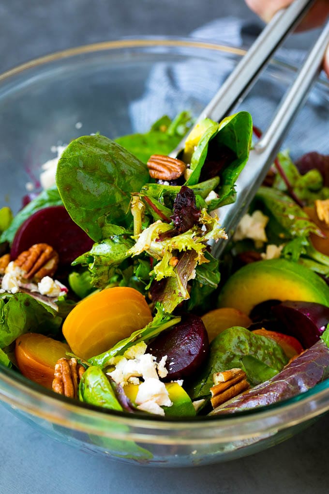 Beet Salad Recipe #beets #avocado #feta #salad #dinner #edsug Tongs serving a portion of beet salad tossed in balsamic dressing.