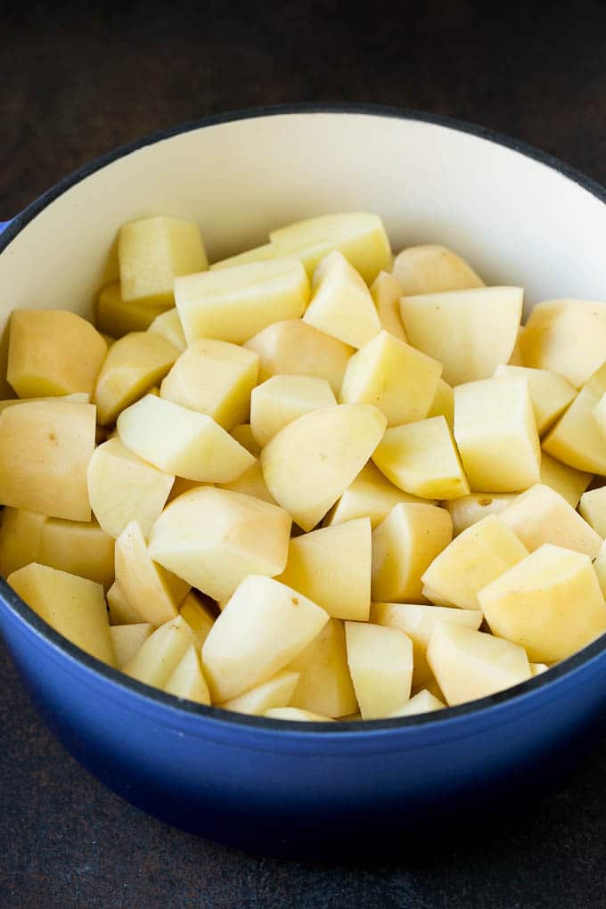 Garlic Mashed Potatoes Recipe #garlic #potatoes #mashedpotatoes #sidedish #dinner #thanksgiving #edsug Diced potatoes in a large blue pot.