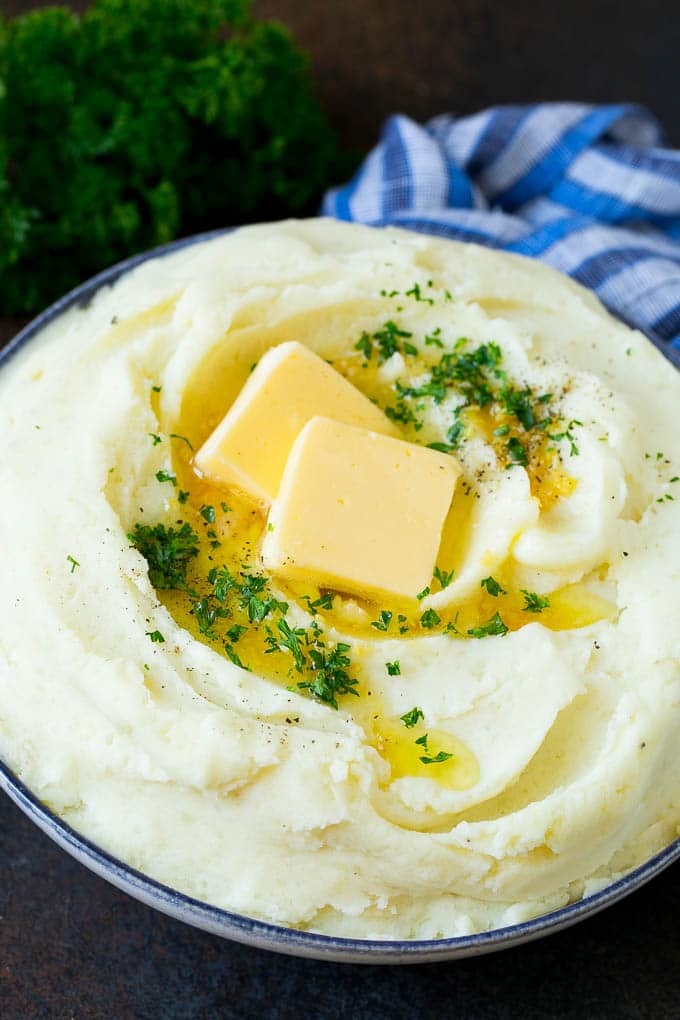 Garlic Mashed Potatoes Recipe #garlic #potatoes #mashedpotatoes #sidedish #dinner #thanksgiving #edsug Garlic mashed potatoes topped with pats of butter and parsley.