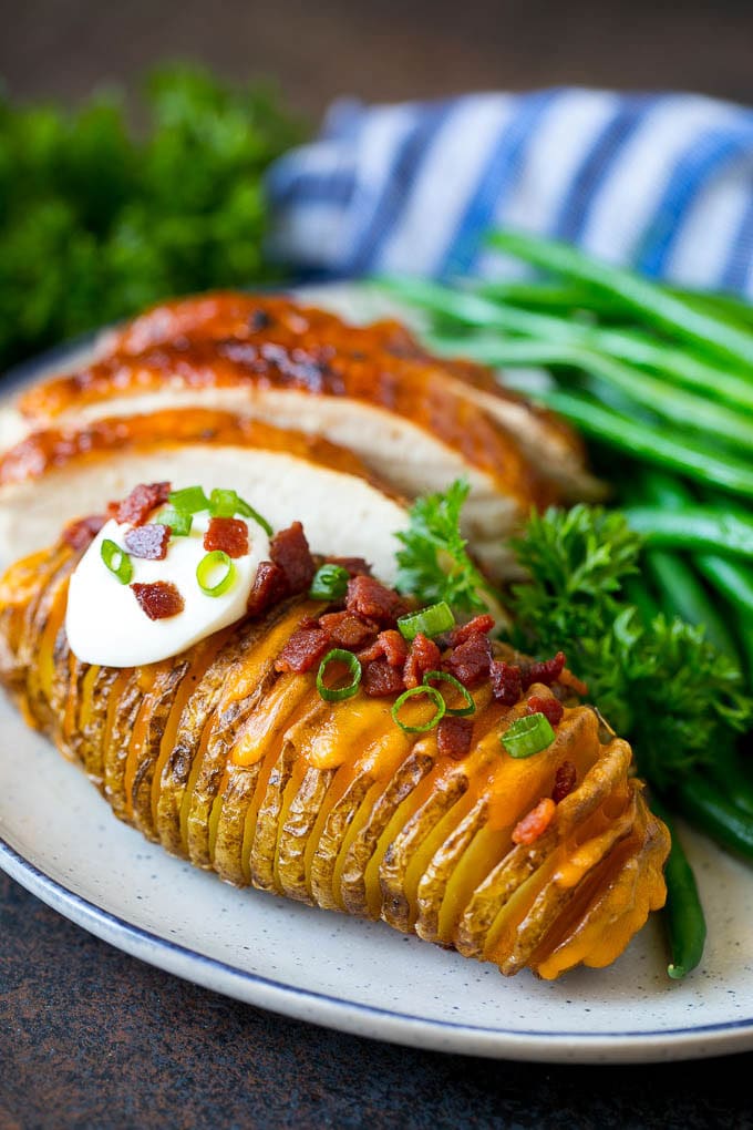 Hasselback Potatoes Recipe #potatoes #bacon #sidedish #cheese #dinner #edsug Hasselback potatoes on a plate, served with turkey and green beans.