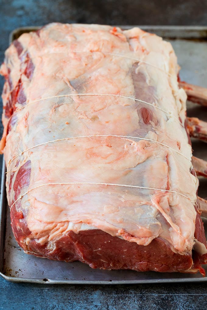 Prime Rib Recipe #primerib #beef #roast #dinner #thanksgiving #christmas #keto #lowcarb #edsug A tied standing rib roast on a sheet pan.
