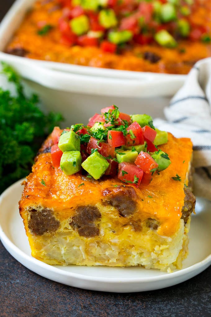 Sausage Egg Casserole Recipe | Egg Casserole #eggs #sausage #potato #cheese #casserole #breakfast #brunch #edsug A slice of sausage egg casserole with a garnish of fresh tomatoes.