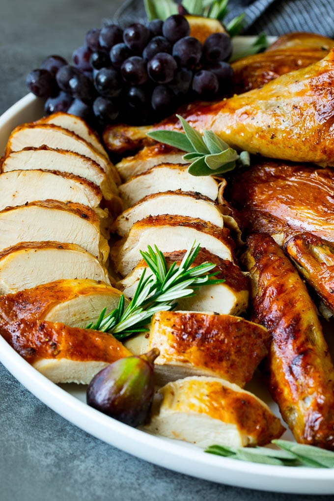 Spatchcock Turkey | Roasted Turkey | Thanksgiving Turkey #turkey #thanksgiving #dinner #fall #christmas #edsug Sliced spatchcock turkey on a serving platter garnished with herbs.
