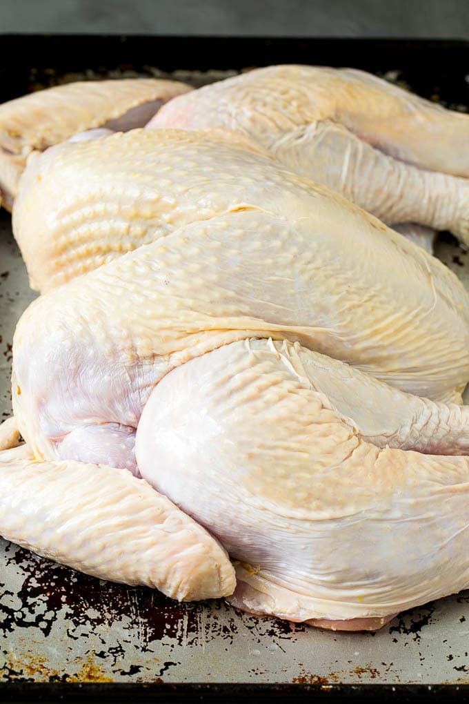 Spatchcock Turkey | Roasted Turkey | Thanksgiving Turkey #turkey #thanksgiving #dinner #fall #christmas #edsug A flattened whole turkey on a sheet pan.