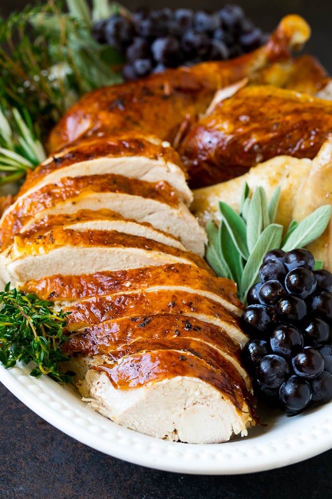 Thanksgiving Turkey Recipe | Roasted Turkey #turkey #thanksgiving #fall #dinner #edsug Sliced Thanksgiving turkey on a serving platter with fresh herbs.
