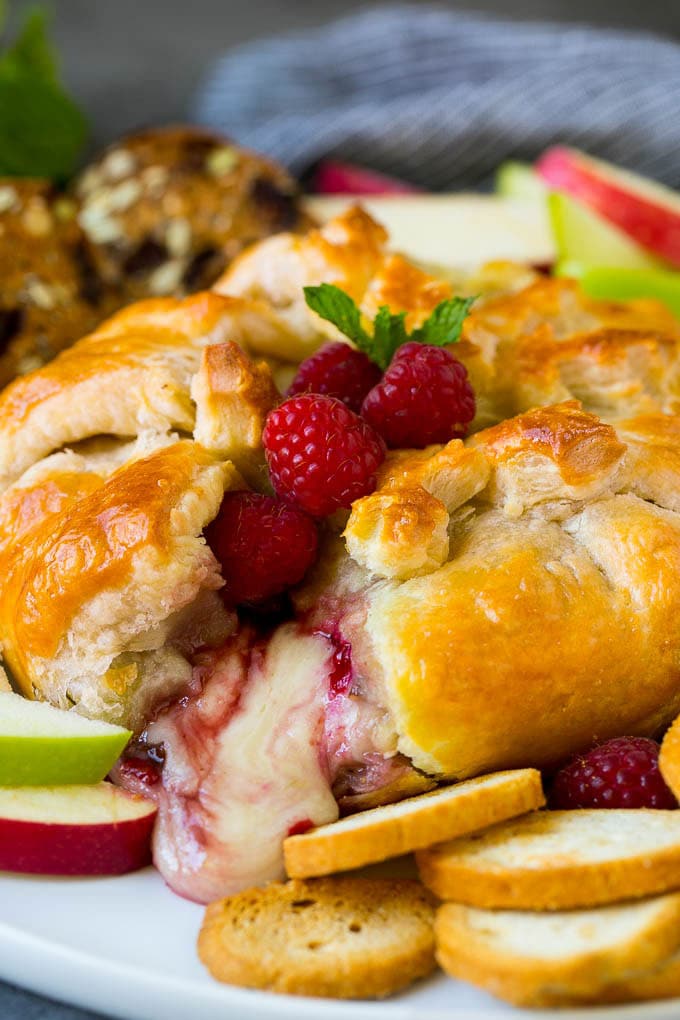 Baked Brie Recipe | Pastry Wrapped Brie #brie #cheese #appetizer #pecans #raspberries #edsug Baked brie cut open with cheese spilling out.