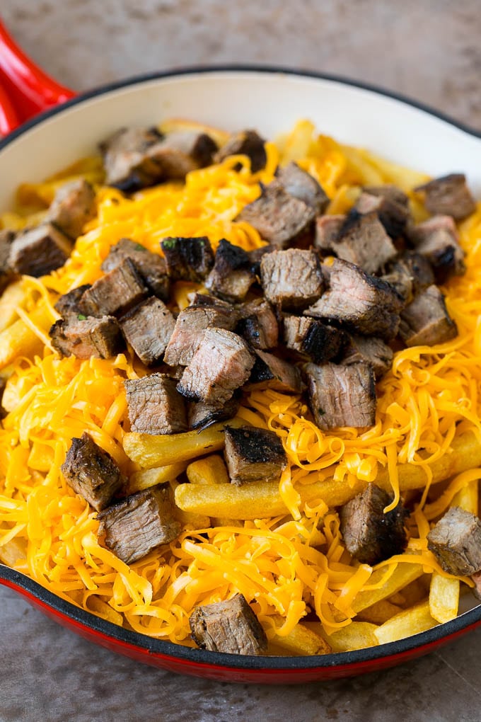 Carne Asada Fries Recipe | Steak Fries #fries #frenchfries #steak #salsa #avocado #cheese #dinner #appetizer #edsug French fries topped with shredded cheese and diced steak.
